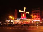 Rot beleuchtete Fassade der Moulin Rouge-Windmühle in der Nacht.