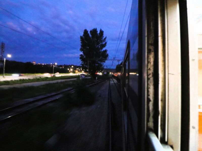 Aus dem offenen Zugfenster – Bahnstrecke kurz nach Sonnenuntergang.