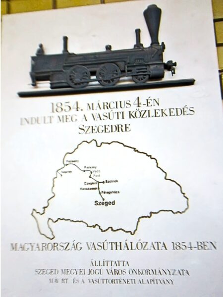 Silberne Metallplakette mit eingraviertem Text "Der Eisenbahnverkehr nach Szeged begann am 4. März 1854. Das Eisenbahnnetz von Ungarn im Jahr 1854. Aufgestellt von der Stadtverwaltung der Stadt Szeged mit Komitatsrechten." Karte der ersten Zugstrecke nach Szeged.