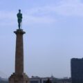 Siegerstatue Pobenik blickt über die Skyline von Novi Beograd. Von hinten fotografiert. East Rail Stories.